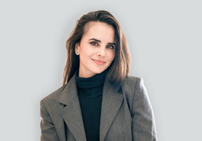 Portrait von Fachärztin für plastische Chirurgie Sofia Rodriguez vor einer hellen Wand